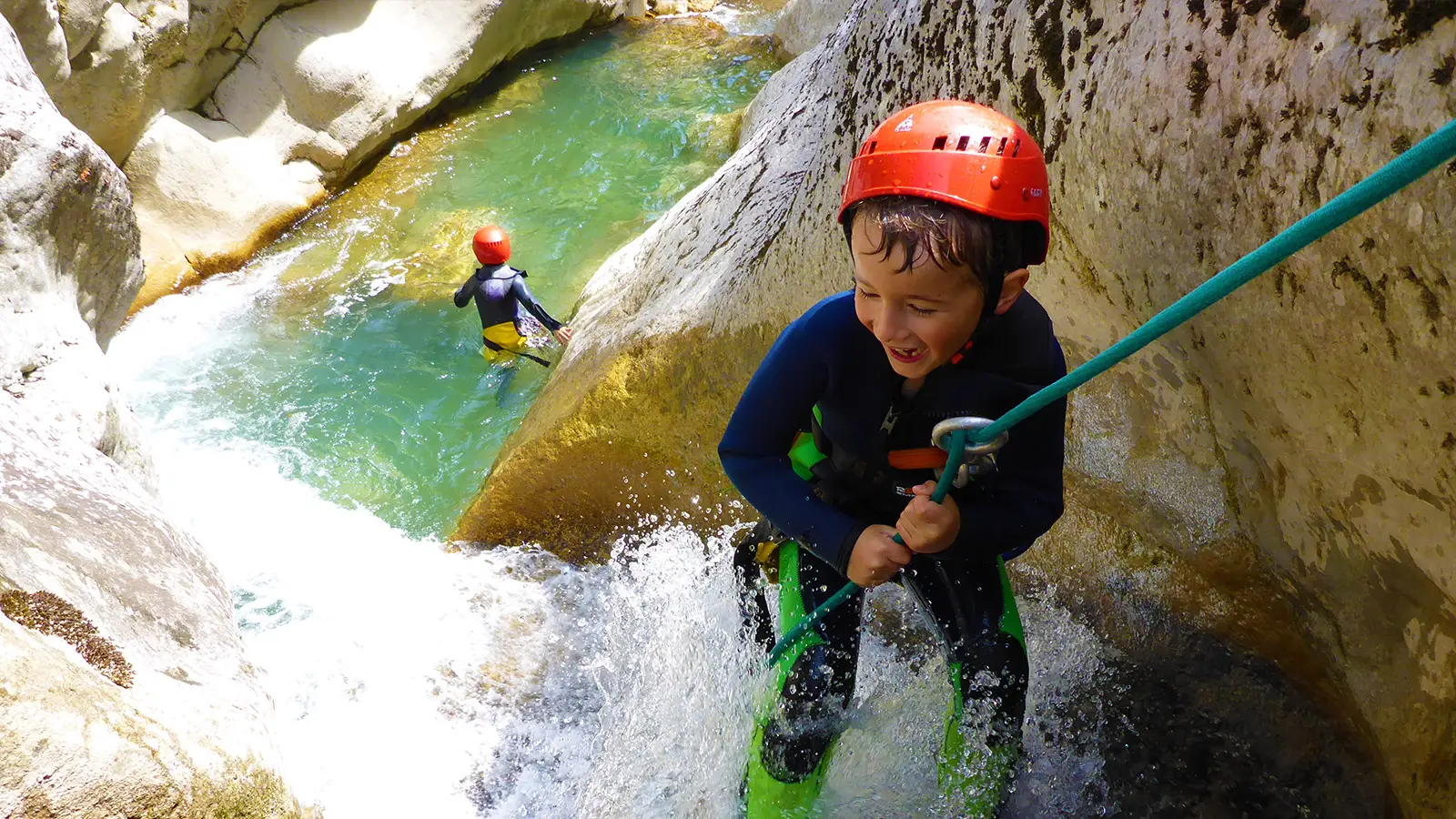 Kid enjoying abseiling down waterfalls in the Gours du Ray canyon close to Gréolières on the french riviera - Les Geckos